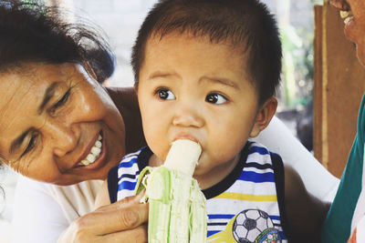 Grandmother feeding banana to grandson