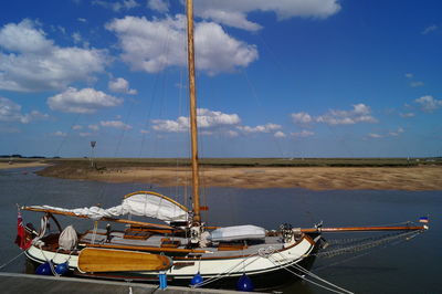 Fishing boats moored at harbor against blue sky