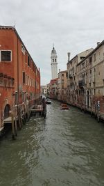 High angle view of canal amidst buildings against cloudy sky