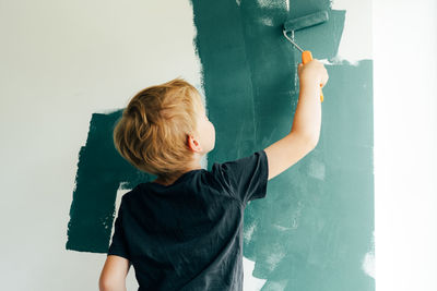 Rear view of boy standing against wall