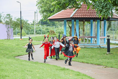 Girls in halloween costumes running on footpath at park