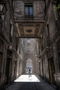 Rear view of woman standing on street by buildings