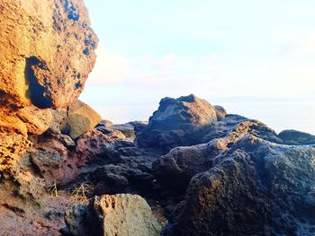 Rock formations on shore against sky