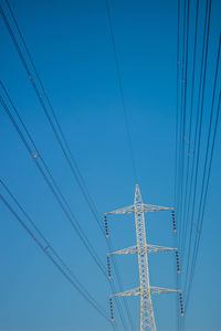 Low angle view of electricity pylon against blue sky