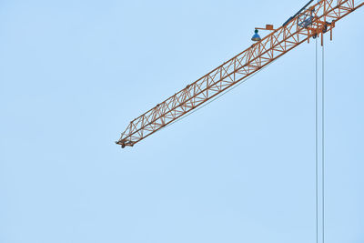 Low angle view of crane against clear blue sky