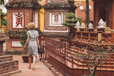 Woman with camera walking on footpath at temple