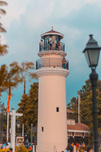 Lighthouse by building against sky