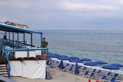 Empty chairs on beach against sky