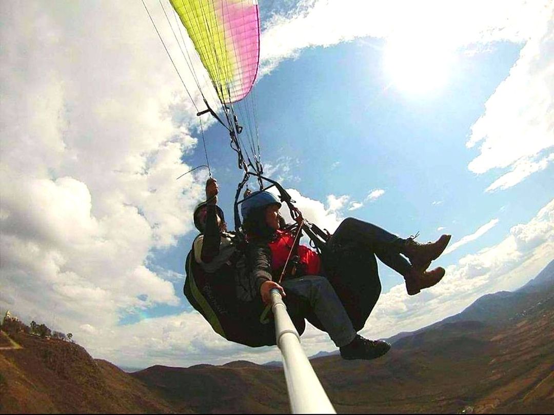 adventure, windsports, air sports, sports, sky, extreme sports, parachute, nature, mountain, leisure activity, cloud, adult, full length, parachuting, one person, mid-air, day, low angle view, tandem skydiving, paragliding, men, joy, safety harness, rope, motion, environment, activity, sunlight, outdoors, vacation, lifestyles, holiday, trip, flying, scenics - nature, risk, exhilaration, landscape, travel, protection, courage, recreation
