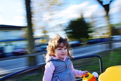 Happy girl enjoying carousel at playground