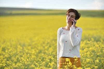 Woman talking on phone while standing on field