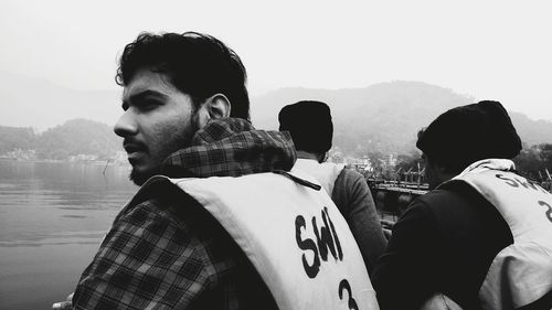 Portrait of young man looking at lake against sky