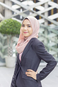 Portrait of confident businesswoman standing with hand on hip against modern office building