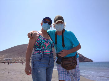 People standing on land against clear blue sky