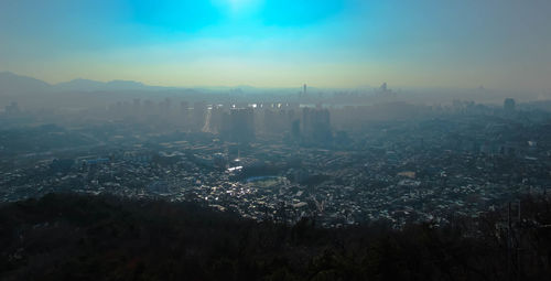 Aerial view of illuminated cityscape against blue sky