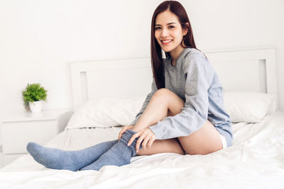 Portrait of a smiling young woman sitting on bed