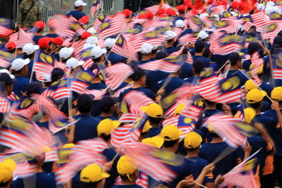 Group of people holding malaysian flag during parade
