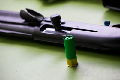 High angle view of shotgun and bullet on table