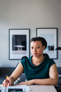 Portrait of confident entrepreneur writing on document at table in office