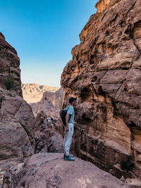 Rear view of man on rock formation against sky