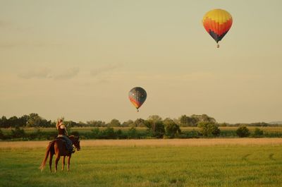 Hot air balloon flying over grassy field