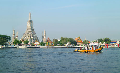 View of wat arun temple on the chao phraya river bank, thonburi district, bangkok, thailand