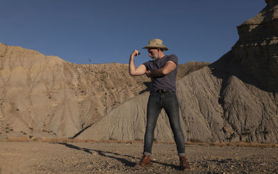 Adult man in cowboy hat on desert against mountain. almeria, spain