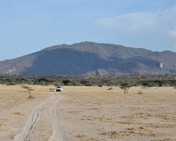 A safari van driving in the scenic mountain views against sky, shaba national reserve, kenya 
