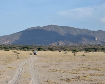 Scenic view of road by mountains against sky