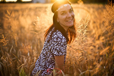 Portrait of smiling woman standing amidst plants at sunset