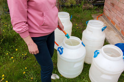 Woman fills a plastic barrel with water from a hose. the concept of the water crisis in the world.