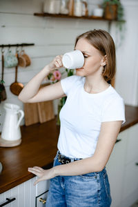 Portrait of young woman drinking water while standing in bathroom