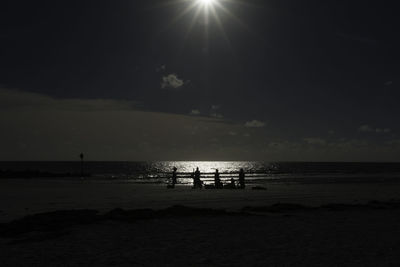 Silhouette people standing on beach against sky