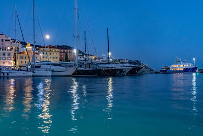 Sailboats in marina at harbor against blue sky