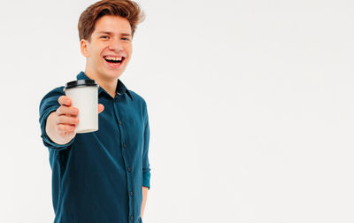 Portrait of smiling man holding coffee cup against white background
