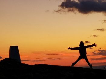 Silhouette person standing on shore against sky during sunset