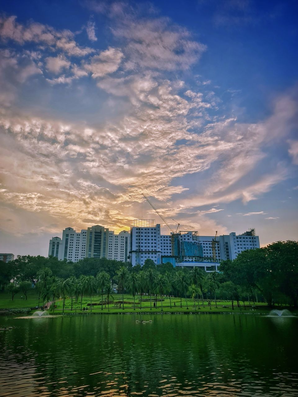 BUILDINGS BY RIVER AGAINST SKY DURING SUNSET