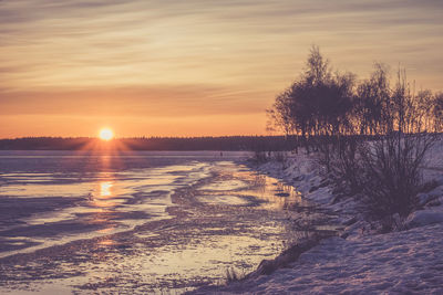 Scenic view of frozen lake against sky during sunset