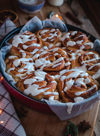 Close-up of homemade cinnamon rolls with cream cheese icing on wooden background