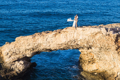 Woman standing on rock by sea