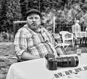 Portrait of man smoking cigar while sitting at table