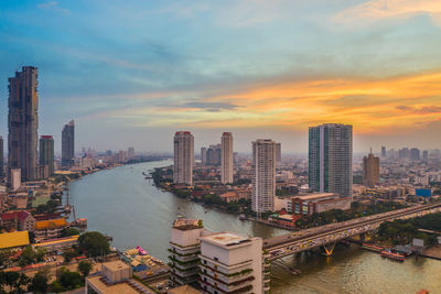 High angle view of river and buildings against sky during sunset