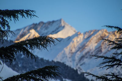 Low angle view of snowcapped mountains against clear blue sky