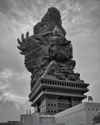 Low angle view of statue of building against cloudy sky