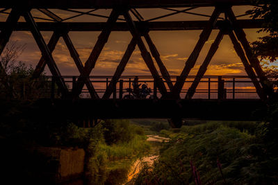 People on bridge against sky during sunset