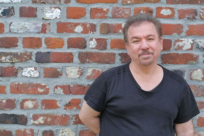 Portrait of man standing against brick wall