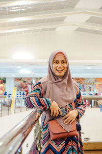 Portrait of smiling young woman standing against wall