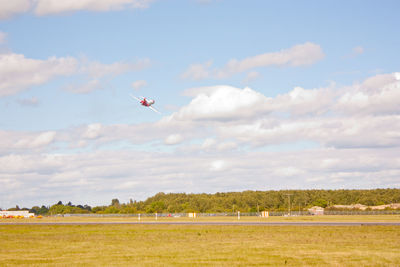 Airplane flying over field against sky