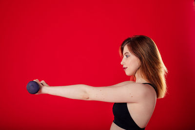 Side view of woman standing against red background