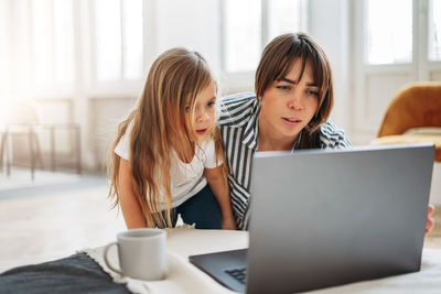 Mother and daughter looking at laptop in room